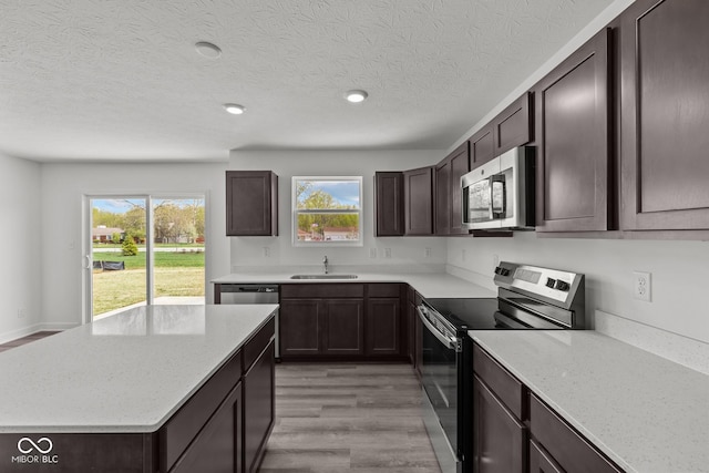 3913 Highcrest Rd, Indianapolis, IN 46239 - kitchen featuring stainless steel appliances, a sink, dark brown cabinets, light wood finished floors, and a textured ceiling