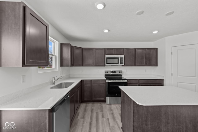 3913 Highcrest Rd, Indianapolis, IN 46239 - kitchen with stainless steel appliances, a sink, light wood-style floors, dark brown cabinets, and light countertops
