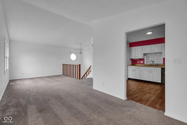 1847 Crystal Bay E Dr, Plainfield, IN 46168 - unfurnished living room with baseboards, dark carpet, a textured ceiling, a ceiling fan, and a sink