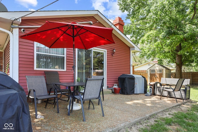 view of patio featuring an outbuilding, area for grilling, fence, and a shed