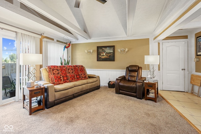 carpeted living area with a wainscoted wall, beamed ceiling, a textured ceiling, and ceiling fan