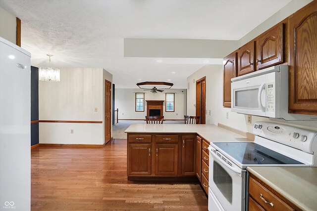 5371 Lue Ann Ln, Mooresville, IN 46158 - kitchen with light countertops, white appliances, baseboards, light wood finished floors, and a peninsula