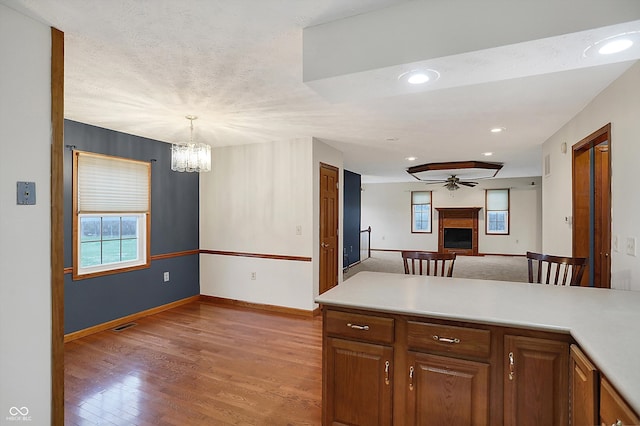 5371 Lue Ann Ln, Mooresville, IN 46158 - kitchen with light countertops, light wood finished floors, a fireplace, open floor plan, and ceiling fan with notable chandelier