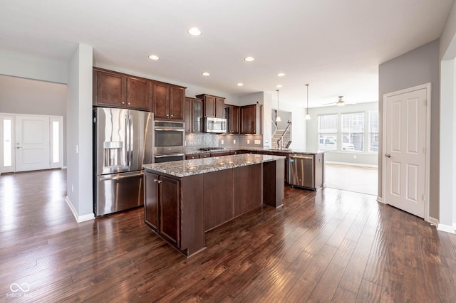 2314 Angelina Way, Greenwood, IN 46143 - kitchen featuring stainless steel appliances, a kitchen island, dark wood-style floors, a peninsula, and dark brown cabinets