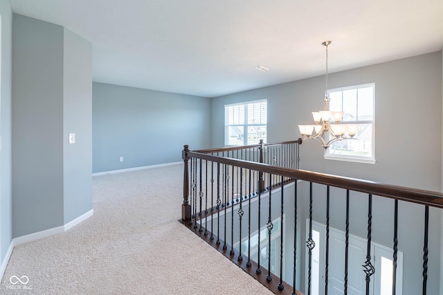 2314 Angelina Way, Greenwood, IN 46143 - hall featuring baseboards, an upstairs landing, carpet flooring, and a chandelier