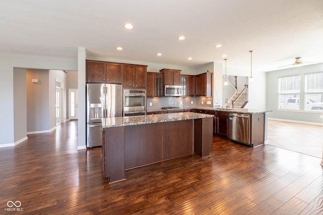 2314 Angelina Way, Greenwood, IN 46143 - kitchen featuring dark wood-style flooring, a peninsula, a kitchen island, appliances with stainless steel finishes, and a sink