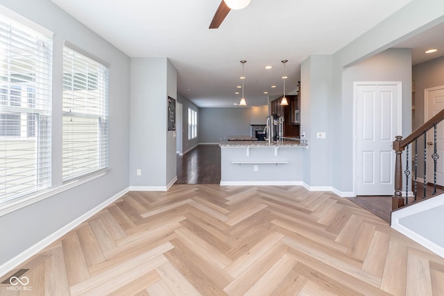 2314 Angelina Way, Greenwood, IN 46143 - interior space with baseboards, light stone countertops, a ceiling fan, and a breakfast bar area