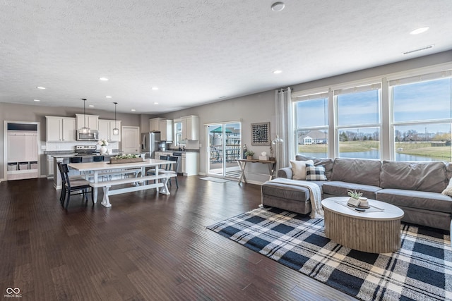 12959 Balfour Rd, Fishers, IN 46037 - living room with a textured ceiling, recessed lighting, dark wood-style floors, a water view, and baseboards