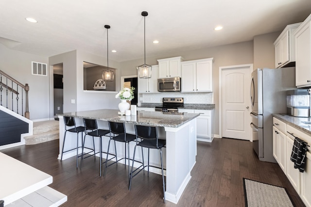 12959 Balfour Rd, Fishers, IN 46037 - kitchen featuring stainless steel appliances, decorative backsplash, dark wood-style flooring, a kitchen island, and white cabinets