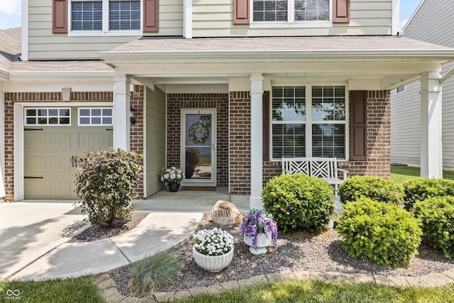 12959 Balfour Rd, Fishers, IN 46037 - view of exterior entry with brick siding, covered porch, a garage, and roof with shingles