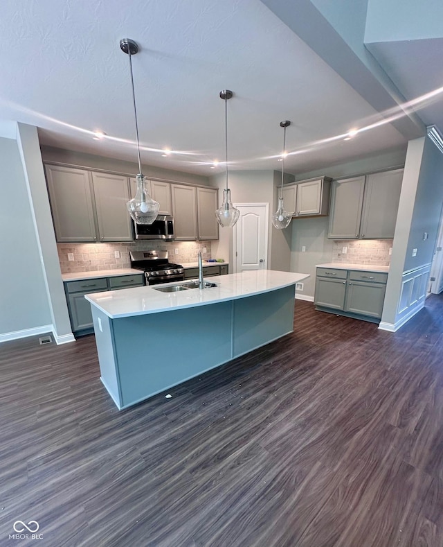 6887 Oakdale Ln, Avon, IN 46123 - kitchen with stainless steel appliances, gray cabinetry, backsplash, a center island with sink, and dark wood-style floors