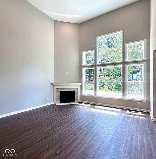 6887 Oakdale Ln, Avon, IN 46123 - unfurnished living room featuring healthy amount of natural light, dark wood-style floors, a fireplace, and a towering ceiling