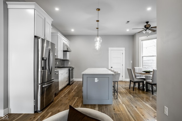 1665 N College Ave, Indianapolis, IN 46202 - kitchen featuring stainless steel appliances, a center island, decorative backsplash, hardwood / wood-style flooring, and white cabinets