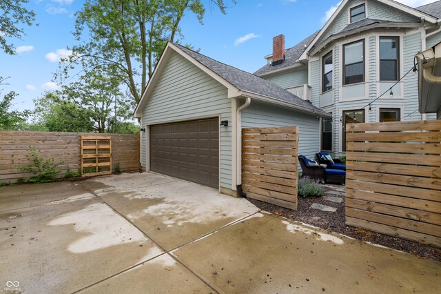 1665 N College Ave, Indianapolis, IN 46202 - view of side of home with roof with shingles, an outdoor structure, fence, a chimney, and concrete driveway
