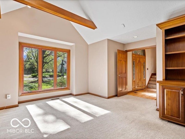unfurnished living room featuring baseboards, lofted ceiling with beams, stairs, and light colored carpet