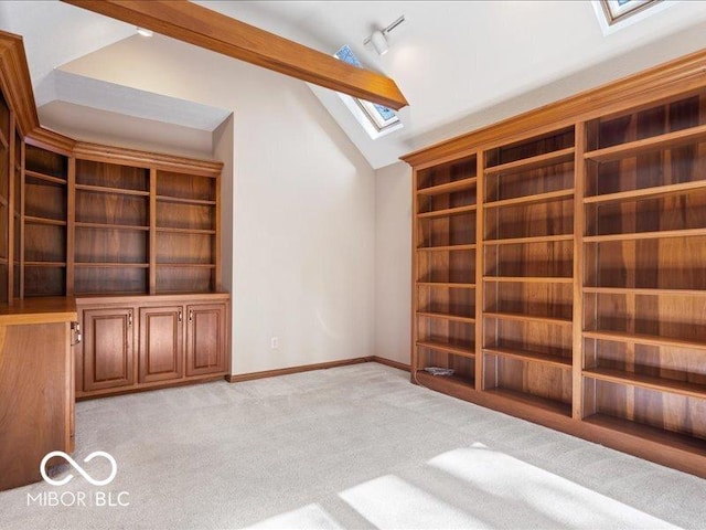 interior space with light colored carpet, baseboards, and vaulted ceiling with skylight