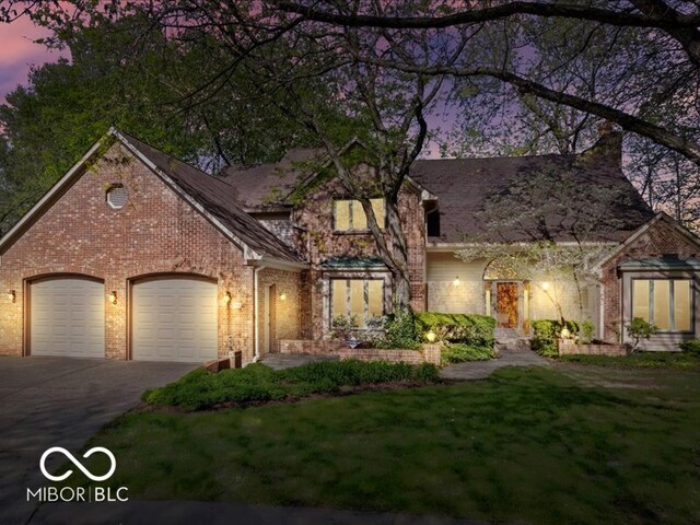 traditional home with a garage, a front yard, brick siding, and aphalt driveway