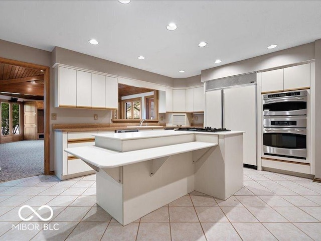 kitchen featuring a kitchen island, stainless steel appliances, white cabinets, and a wealth of natural light