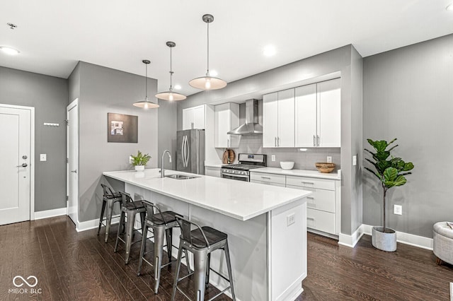 622 E 10th St Unit 206, Indianapolis, IN 46202 - kitchen with wall chimney exhaust hood, stainless steel appliances, dark wood finished floors, a breakfast bar area, and baseboards