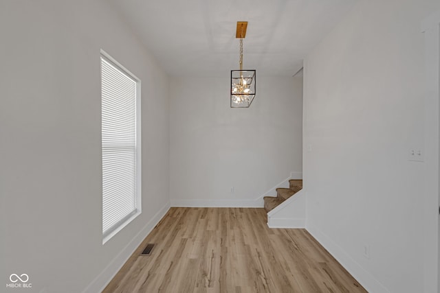 843 N Oxford St, Indianapolis, IN 46201 - unfurnished dining area with light wood-style floors, a chandelier, and stairs
