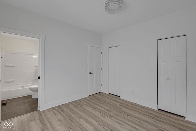 843 N Oxford St, Indianapolis, IN 46201 - unfurnished bedroom featuring light wood-type flooring, ensuite bath, and two closets