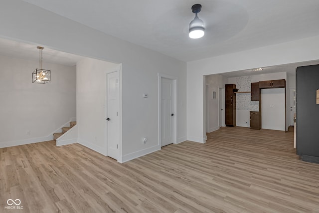 843 N Oxford St, Indianapolis, IN 46201 - unfurnished living room featuring stairway, light wood-style flooring, and a chandelier