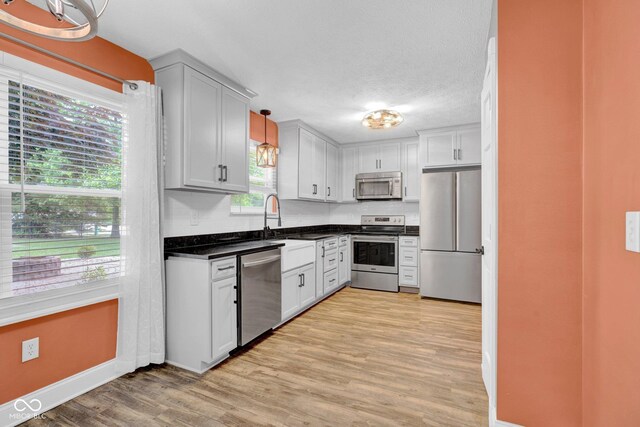 7383 Poppyseed Dr, Indianapolis, IN 46237 - kitchen with stainless steel appliances, baseboards, dark countertops, light wood-style floors, and a sink