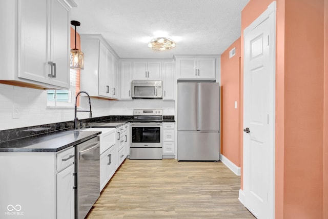 7383 Poppyseed Dr, Indianapolis, IN 46237 - kitchen featuring stainless steel appliances, dark countertops, light wood-style floors, white cabinetry, and a textured ceiling