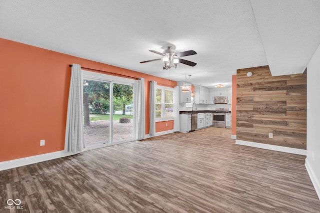 7383 Poppyseed Dr, Indianapolis, IN 46237 - unfurnished living room with ceiling fan, baseboards, wood finished floors, a textured ceiling, and wooden walls