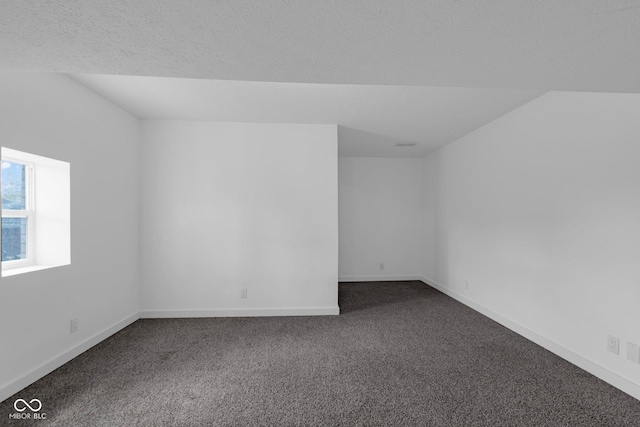 empty room featuring dark carpet and baseboards