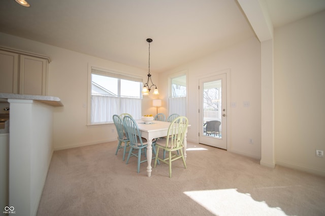 dining space featuring light colored carpet, baseboards, and a chandelier