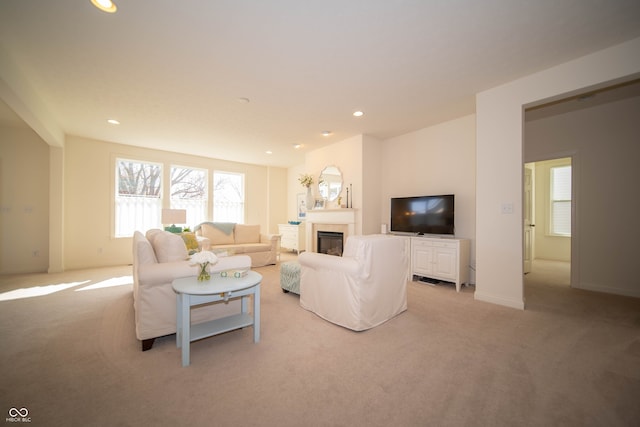 living area with recessed lighting, baseboards, a glass covered fireplace, and light carpet