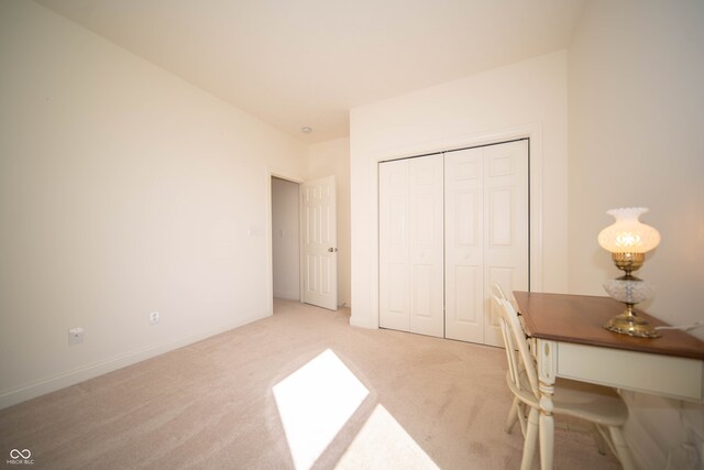 bedroom featuring baseboards, a closet, and light colored carpet