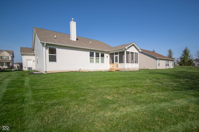 rear view of property featuring a yard, a chimney, and a sunroom
