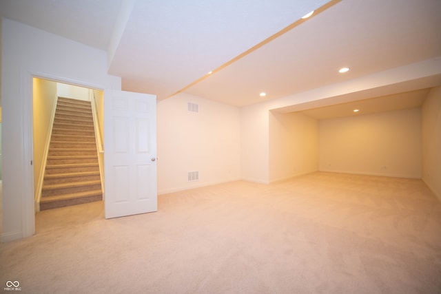 finished basement with stairs, recessed lighting, visible vents, and light carpet