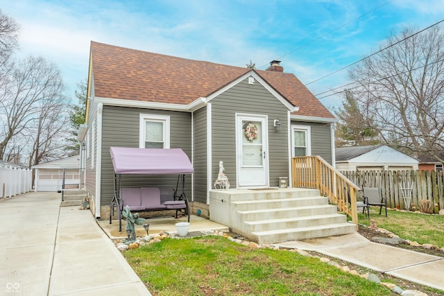 bungalow-style house featuring a hot tub, roof with shingles, fence, and a chimney