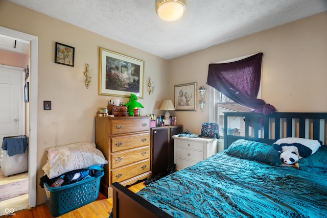 bedroom with a textured ceiling and wood finished floors