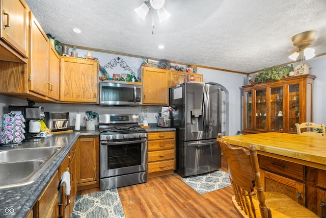 kitchen with light wood-style floors, a ceiling fan, stainless steel appliances, and a textured ceiling