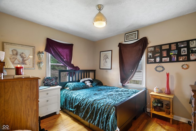 bedroom with a textured ceiling and wood finished floors