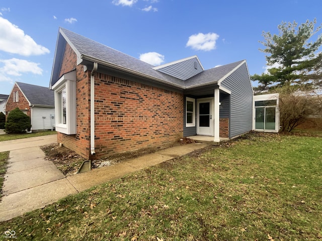 view of side of home with brick siding and a lawn
