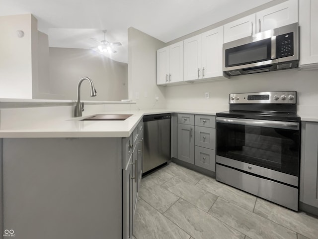 kitchen with light countertops, a sink, gray cabinets, and appliances with stainless steel finishes