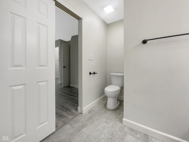 bathroom with toilet and baseboards