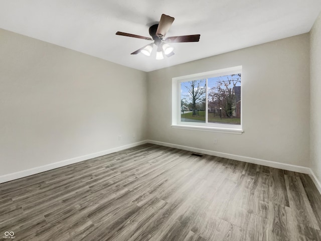 unfurnished room featuring baseboards, visible vents, wood finished floors, and a ceiling fan