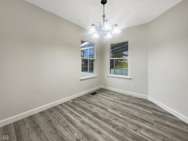 empty room featuring baseboards, a chandelier, and dark wood finished floors