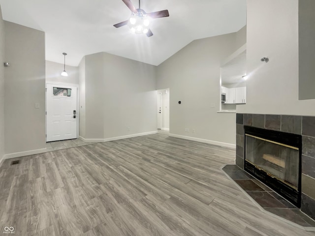 unfurnished living room featuring baseboards, vaulted ceiling, light wood-type flooring, and a ceiling fan