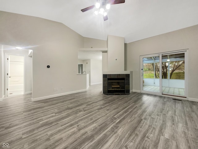 unfurnished living room featuring a ceiling fan, baseboards, vaulted ceiling, and wood finished floors