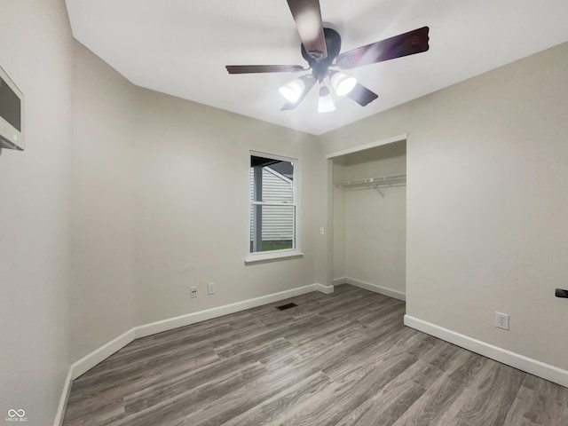 unfurnished bedroom featuring baseboards, visible vents, a ceiling fan, a closet, and wood finished floors