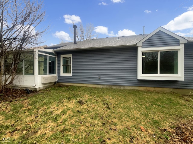 view of property exterior featuring a lawn, a sunroom, and roof with shingles