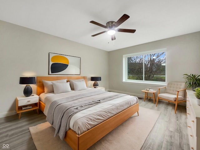 bedroom featuring baseboards, wood finished floors, and ceiling fan