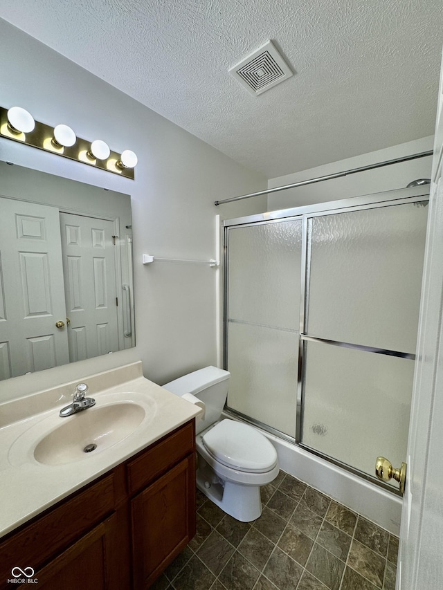 bathroom with vanity, visible vents, an enclosed shower, a textured ceiling, and toilet